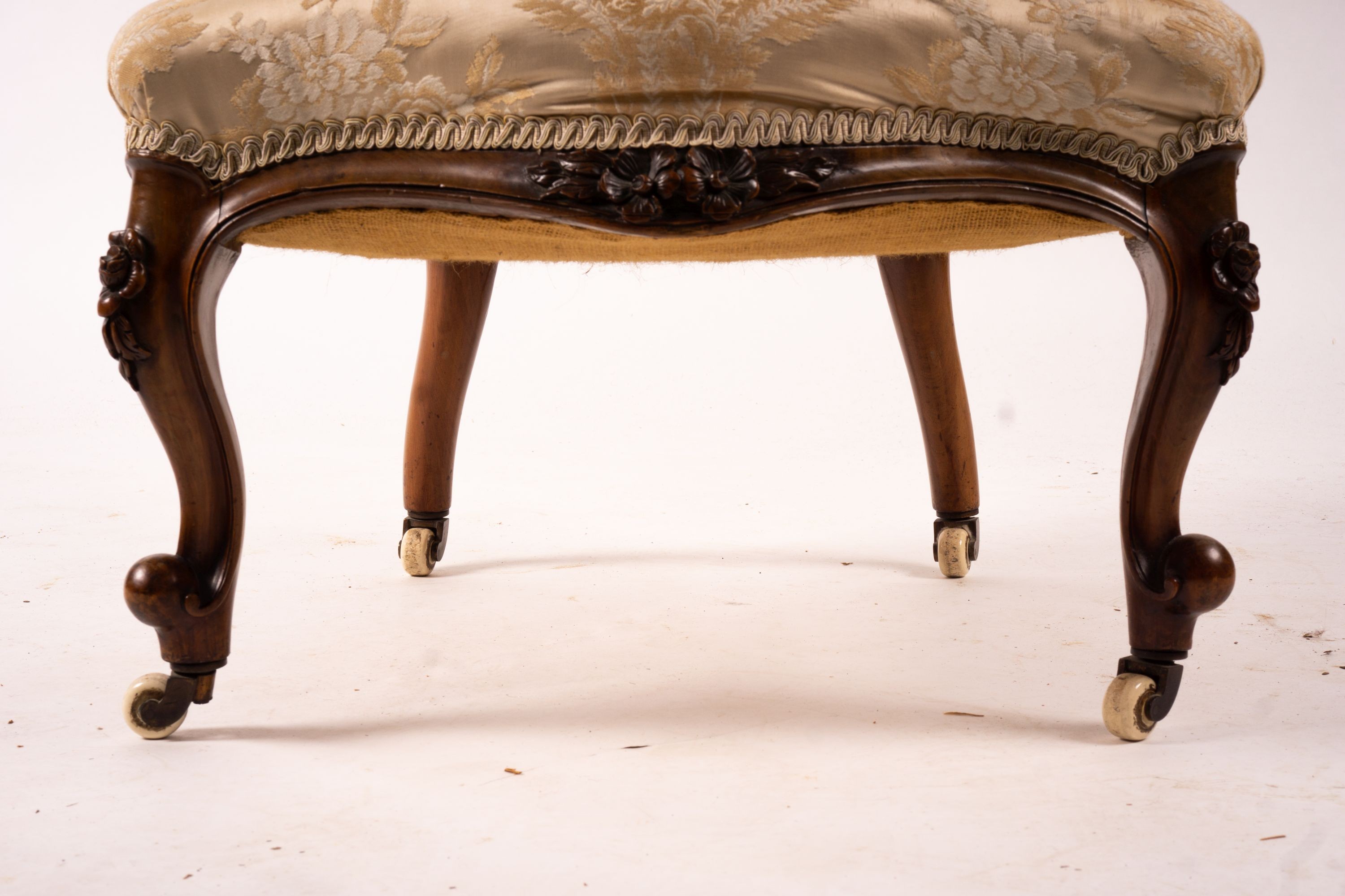 A late Victorian carved walnut three piece salon suite, comprising chaise longue, open armchair and nursing chair